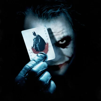 Face-painted villain holding a playing card with a bat silhouette in a gloved hand