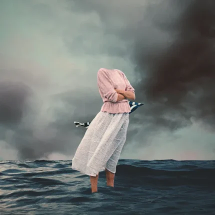 Woman in pink top and white skirt standing in stormy sea under dark clouds