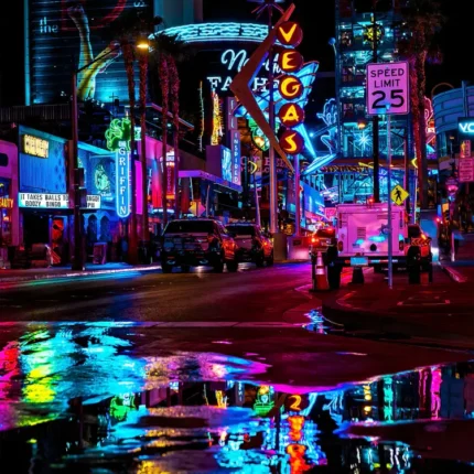 Neon signs reflected in rain puddles on a Las Vegas street at night