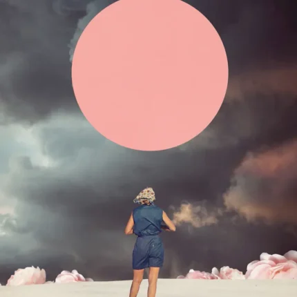 Woman in blue standing on white sand facing a giant pink circle under dark stormy clouds