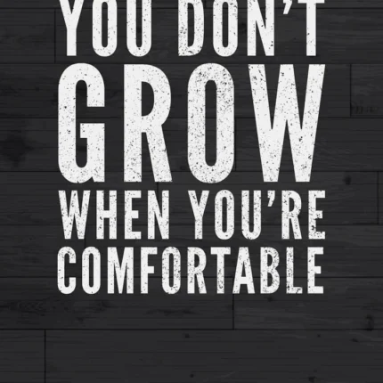 White text You Don't Grow When You're Comfortable on a dark wood background