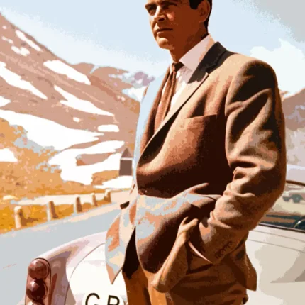 Man in a brown suit beside a vintage silver car with snowy mountains behind
