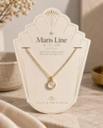 Art deco cream card holding a gold necklace with a small round white pendant