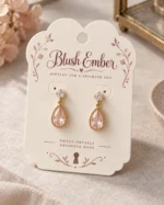 Cream card with pink floral border holding gold-framed pink teardrop earrings