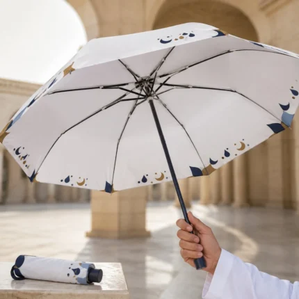Cream folding umbrella with navy and gold crescent print held open in a courtyard