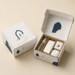 Cream mailer box with navy motifs open to show a Hajj essentials kit