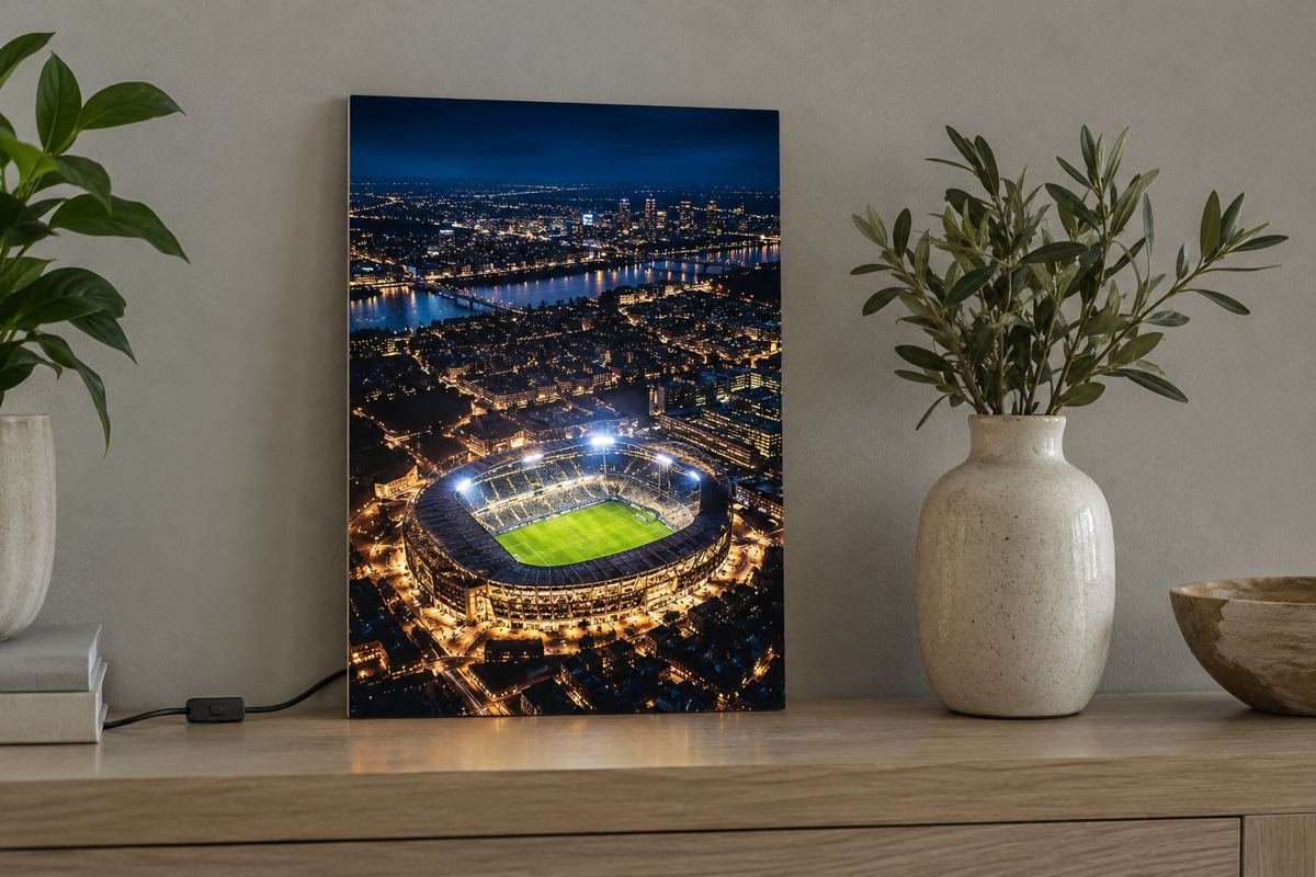 Illuminated stadium artwork beside a television in a home football watch corner